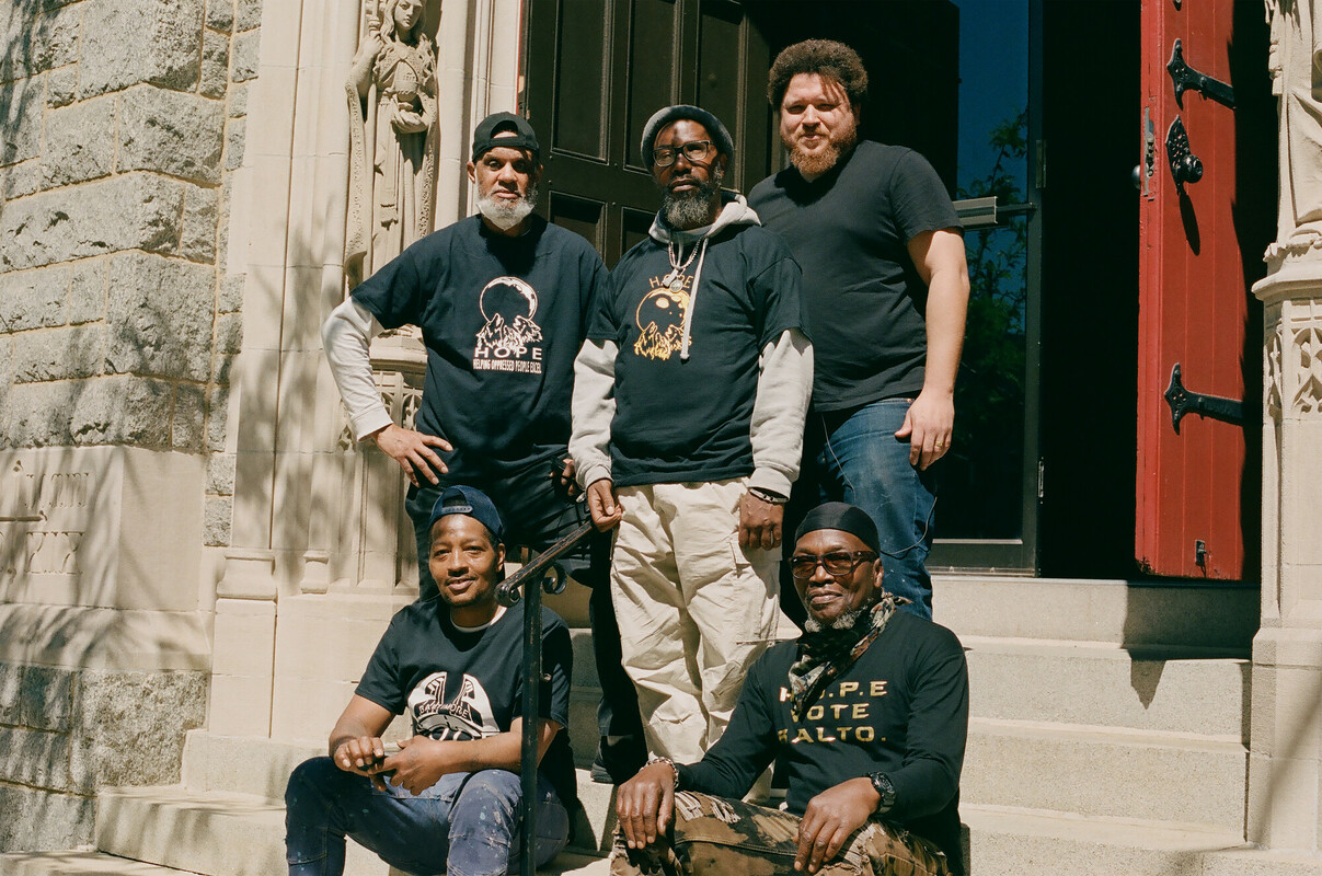 Men of color posing for a photo on the steps of a building