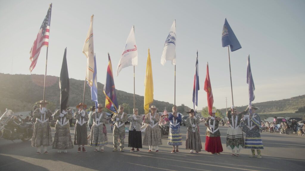 Women in camouflage, holding up various flags